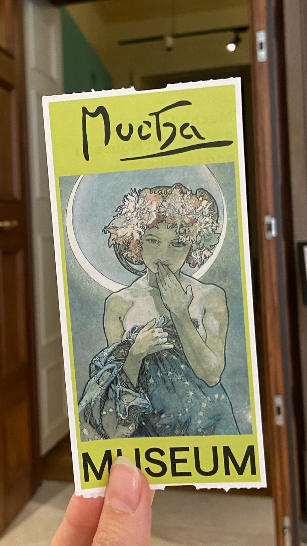 Hand holding a museum ticket in the backgroun framing the ticket is the entrance door.